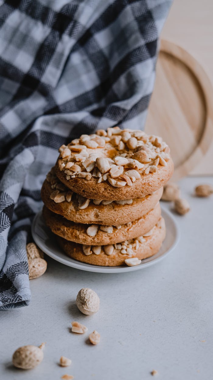 A stack of nut-covered biscuits on a white plate with a rustic background.